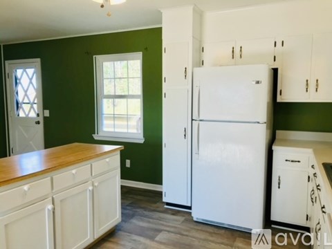 A white refrigerator in a kitchen with green walls.