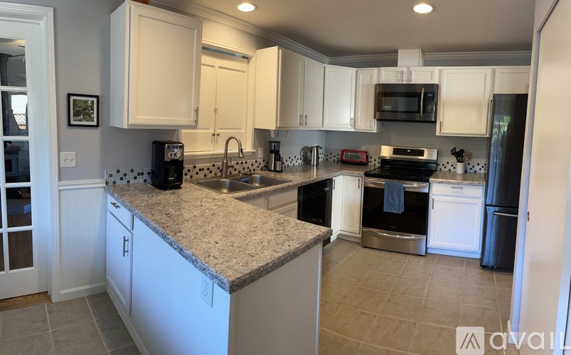A kitchen with white cabinets and a granite countertop.