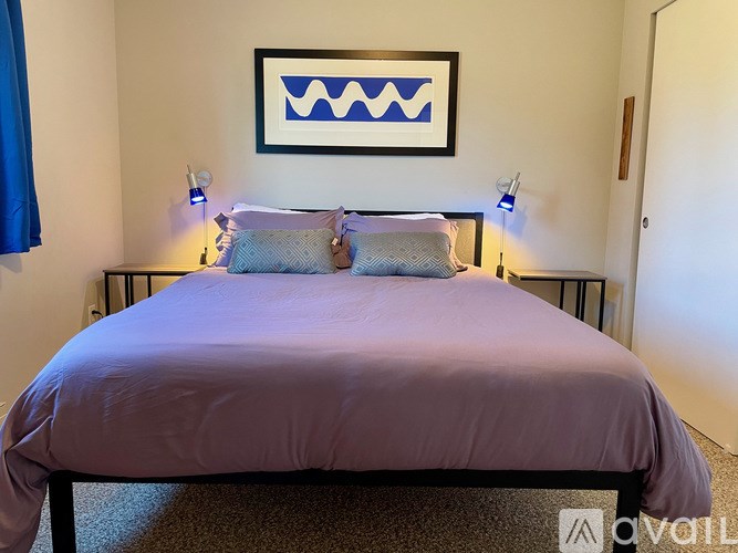 A bed with a purple cover and two blue pillows.