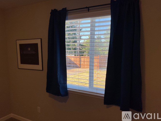 A window with black curtains and a picture on the wall.