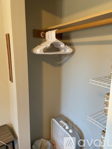 A white shoe is hanging on a wooden hanger.