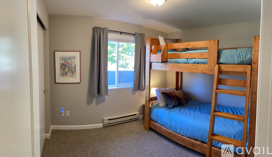 A bedroom with a bunk bed and a window with curtains.