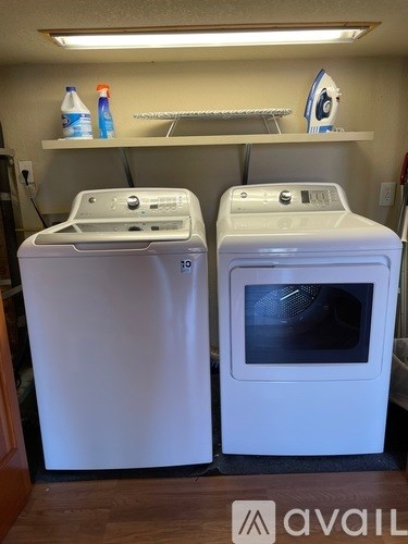 Two white front loading washing machines in a laundry room.