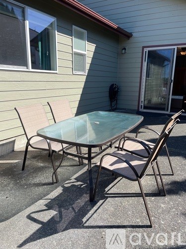 A glass table and two chairs are on a patio.