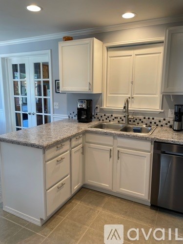 A kitchen with white cabinets and a granite countertop.