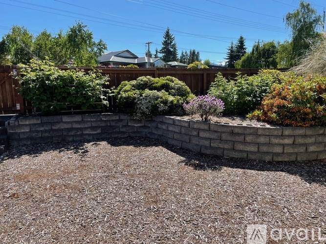 A backyard with a gravel area and a retaining wall.
