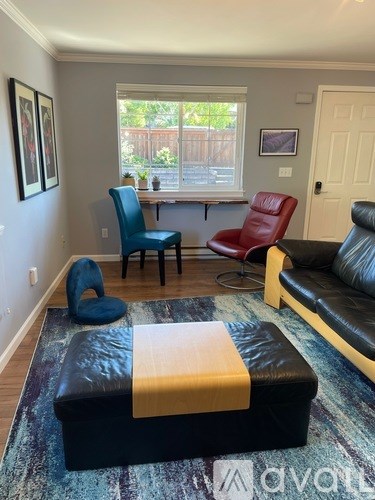 A living room with a black ottoman and a blue chair.