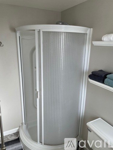 A white shower stall with a glass door is in a bathroom.