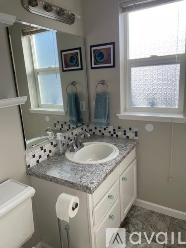 A bathroom with a sink, toilet, and a window.