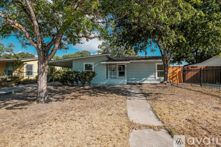A house with a white fence and a tree in front of it.