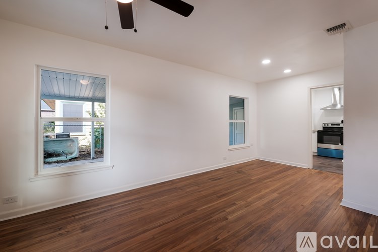 A room with wooden floors and a window overlooking a backyard.