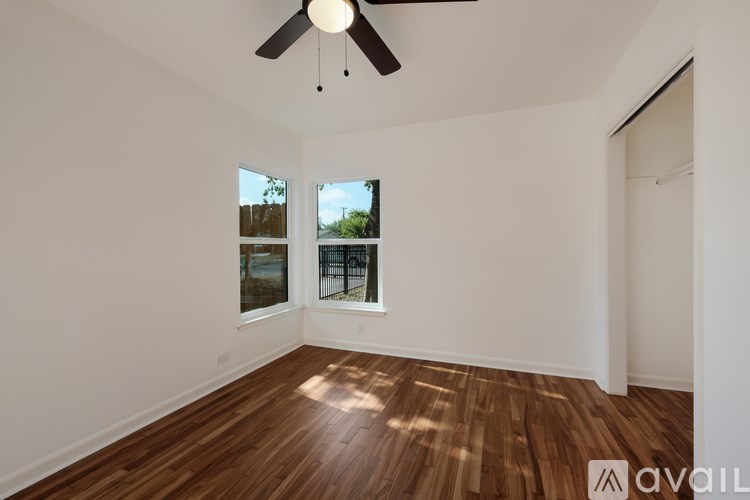 A room with a ceiling fan and wooden flooring.
