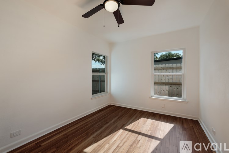 A room with wooden floors and two windows.