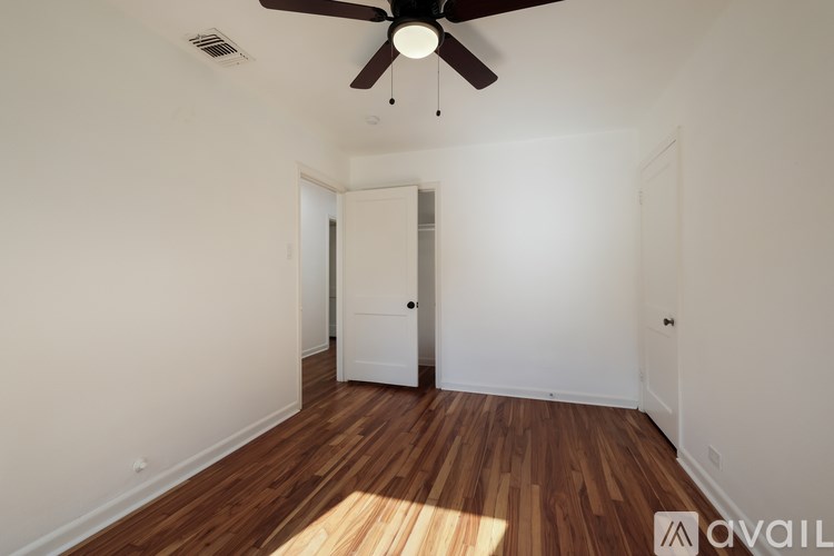 A room with a ceiling fan and wooden floors.