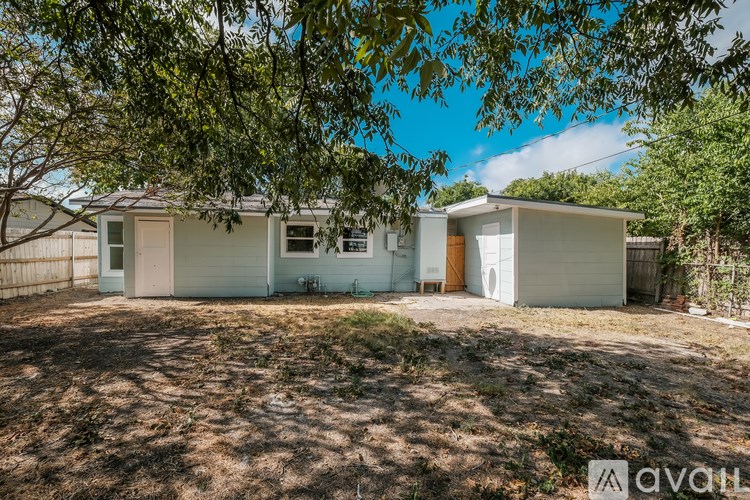 A white house with a brown door is surrounded by trees.