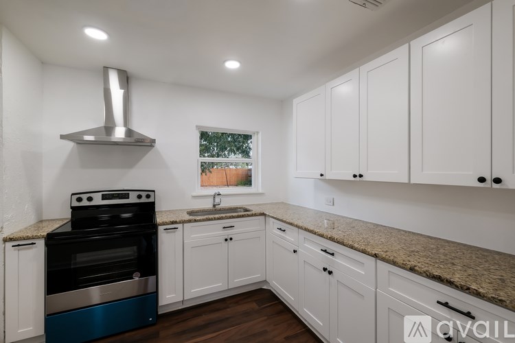 A kitchen with white cabinets and a stainless steel range hood.