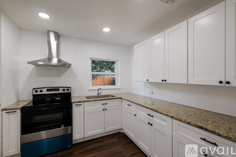 A kitchen with white cabinets and a stainless steel range hood.
