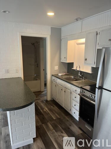 A kitchen with white cabinets and a black countertop.