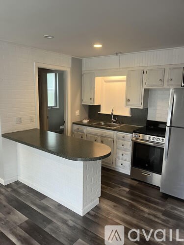 A kitchen with a black countertop and stainless steel appliances.