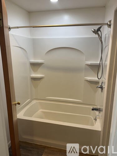 A white bathroom with a bathtub and a shower head.