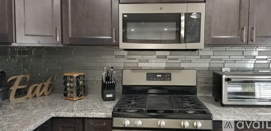 A modern kitchen with a stove top oven and a microwave above it.