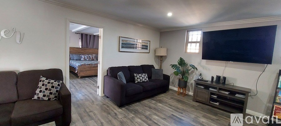 A living room with a brown couch and a flat screen TV mounted on the wall.