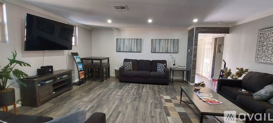 A living room with a grey couch and a television mounted on the wall.