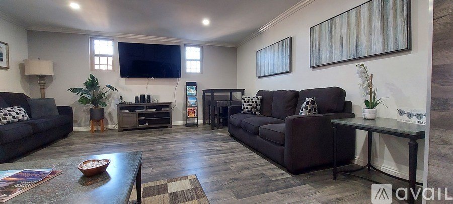 A living room with a large couch, a coffee table, and a flat-screen TV mounted on the wall.