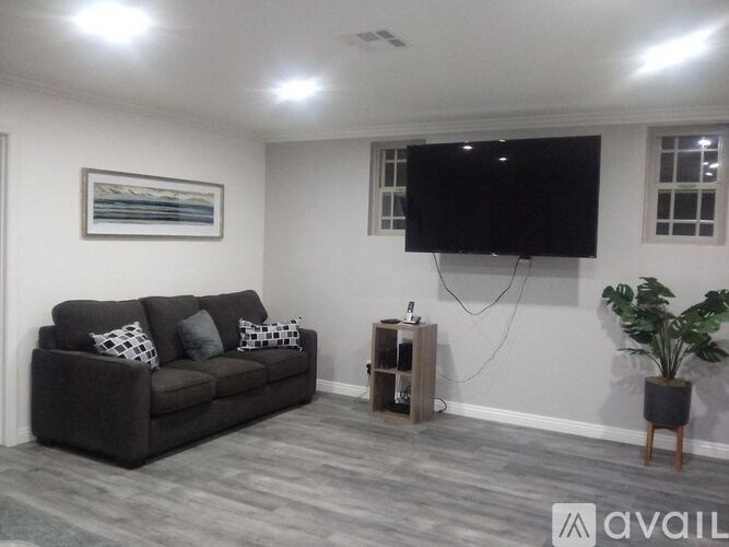 A living room with a grey couch and a flat screen TV mounted on the wall.