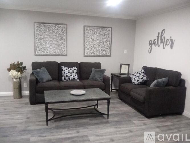 A living room with a sofa, coffee table, and two decorative pictures on the wall.