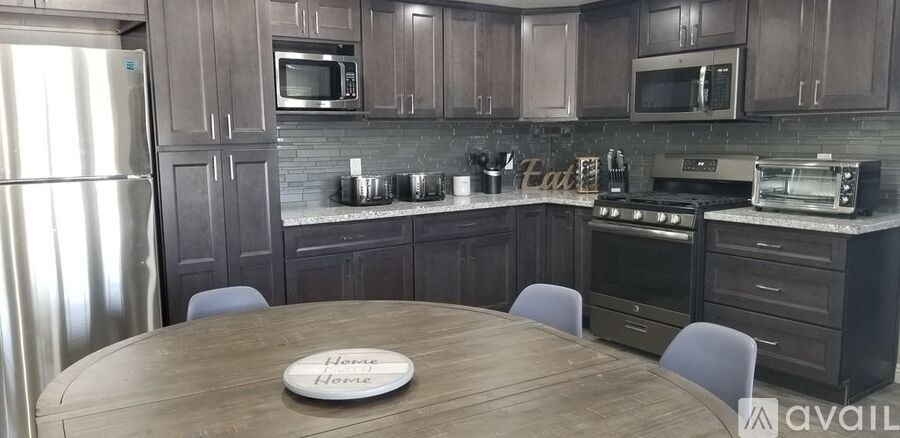 A kitchen with a wooden table and chairs, and a sign that says "Home Sweet Home".