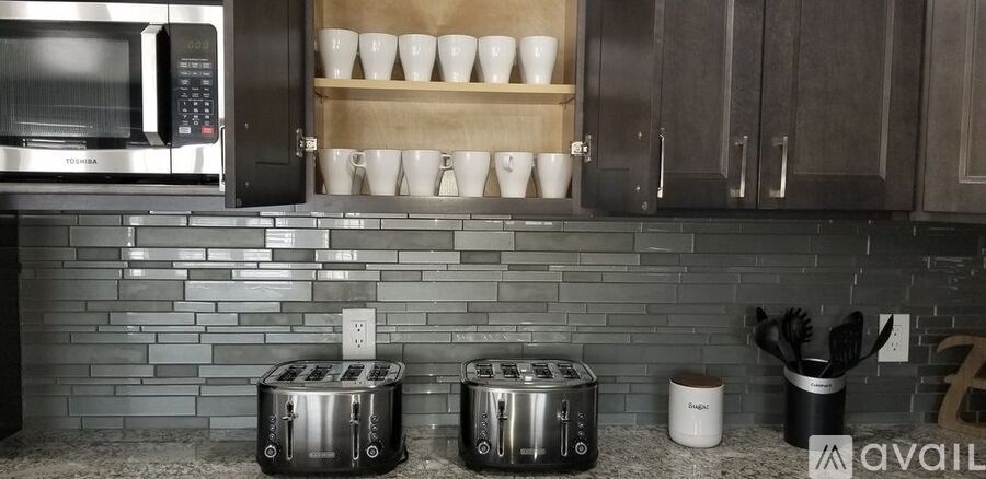 A kitchen with two toasters on the counter.