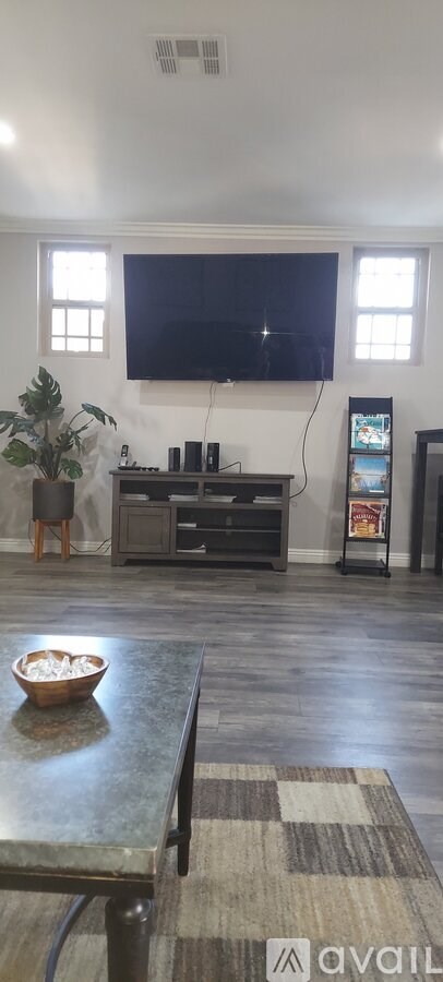 A living room with a television mounted on the wall and a bowl on the coffee table.
