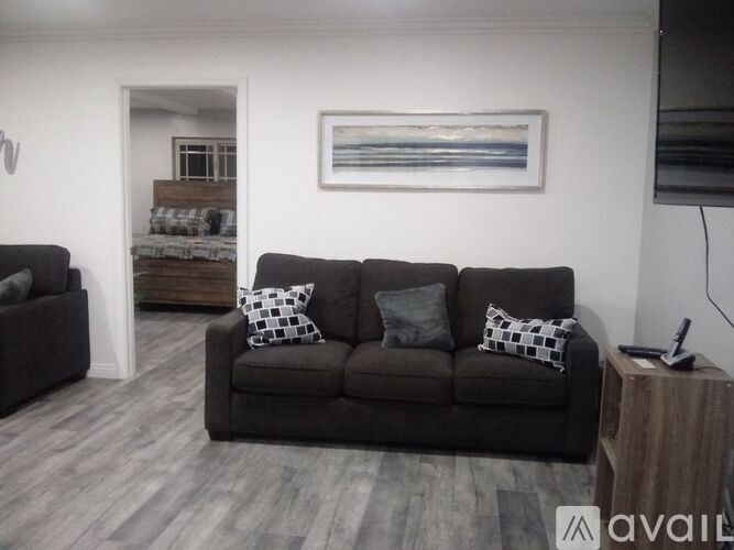 A living room with a grey couch and a painting on the wall.