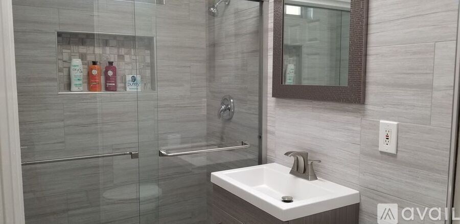A bathroom with a white sink and a glass shower stall.