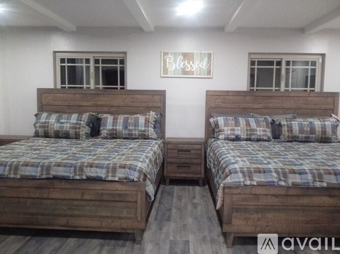 Two beds with pillows and a sign that says "Blessed" on the wall.