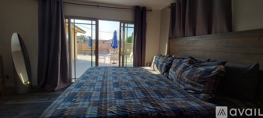 A bedroom with a large bed and a view of the backyard through the sliding glass doors.