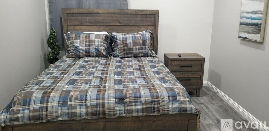 A bed with a wooden headboard and a plaid comforter is in the image.