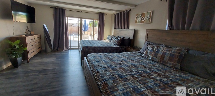 A bedroom with two beds and a dresser with a flat screen TV mounted above it.