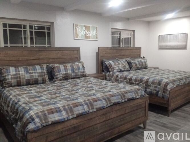 Two beds with plaid bedspreads in a room with white walls.
