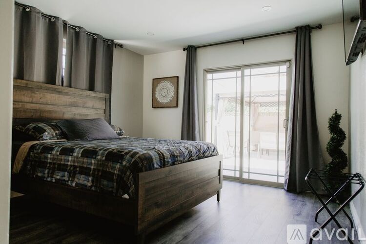A bedroom with a large bed and a window with curtains.