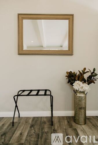 A chair with a black metal frame sits in front of a mirror and a vase with flowers.