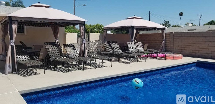 A pool with a ball in it and chairs around it.