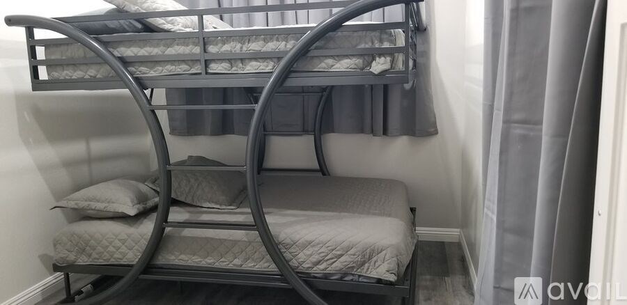 A grey bunk bed with a single bed underneath it.
