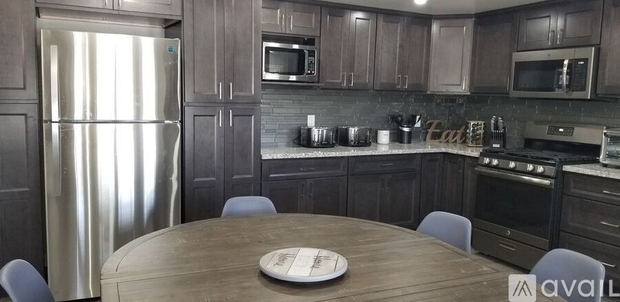 A kitchen with a table in the middle and a refrigerator on the left.