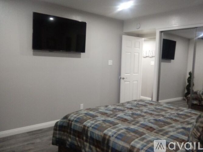 A bedroom with a bed, a television, and a mirror.