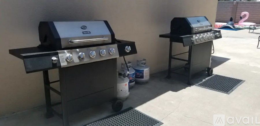 Two grills are on a patio.