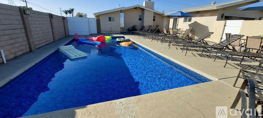 A pool with a blue tinted water and a few inflatable toys floating on it.