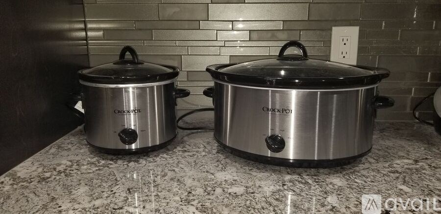 Two stainless steel slow cookers on a kitchen counter.