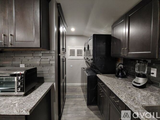 A modern kitchen with dark wood cabinets and stainless steel appliances.